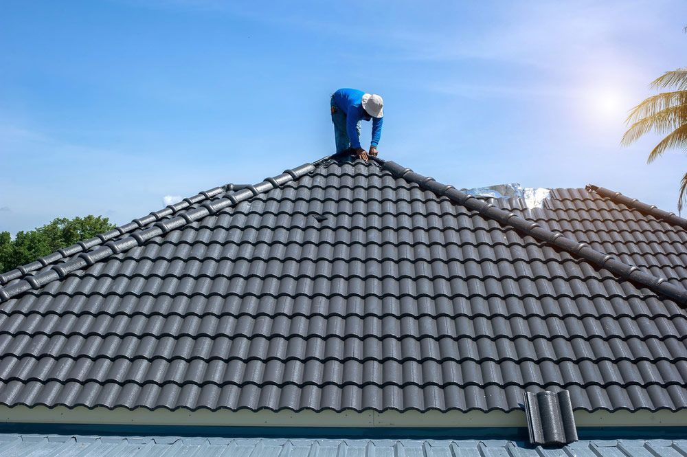 A Man is Working on the Roof of a House — East Coast Roof Tiling Services in Kuluin, QLD