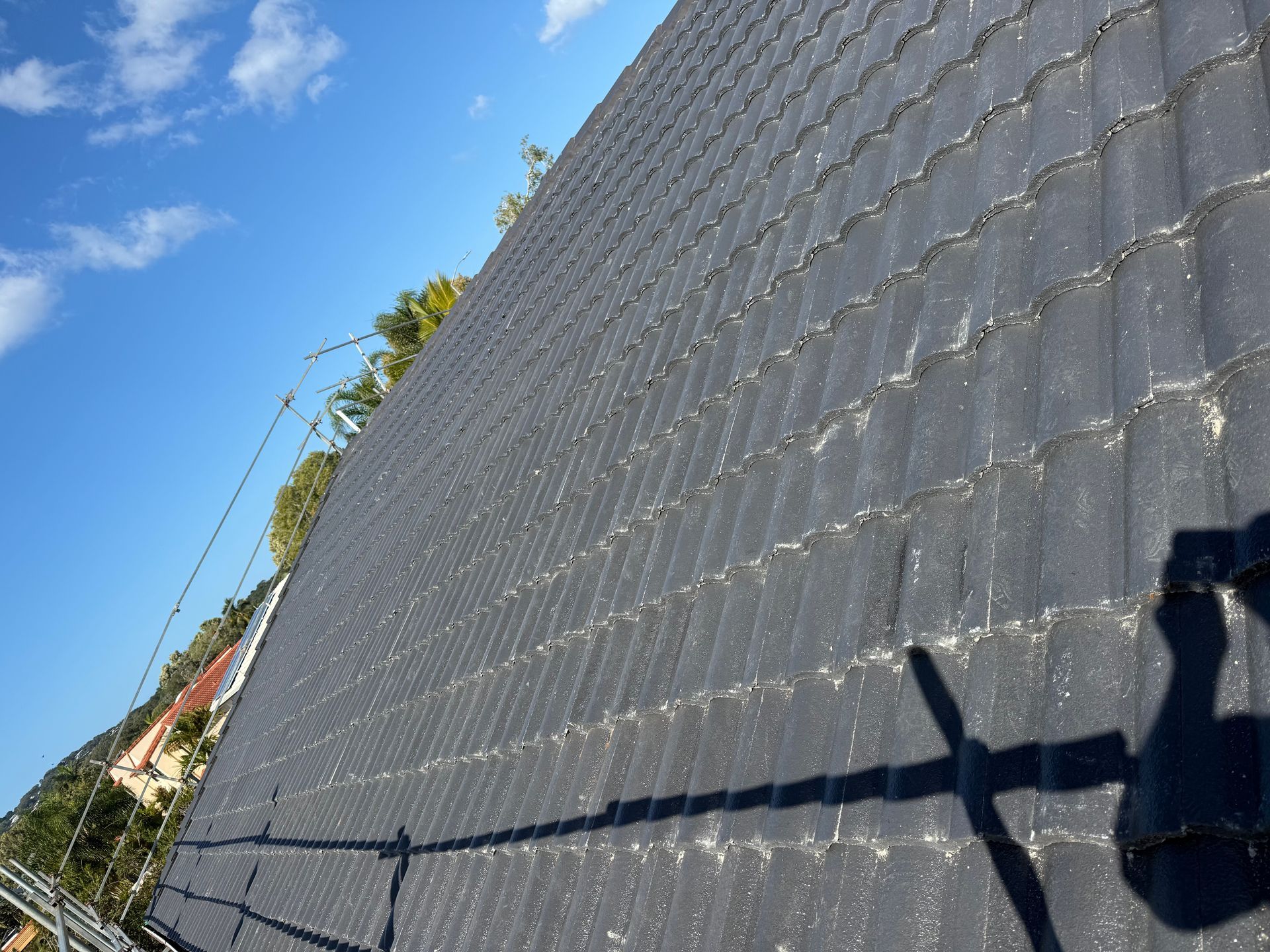 A Person Wearing Yellow Gloves is Working on a Roof — East Coast Roof Tiling Services in Kuluin, QLD