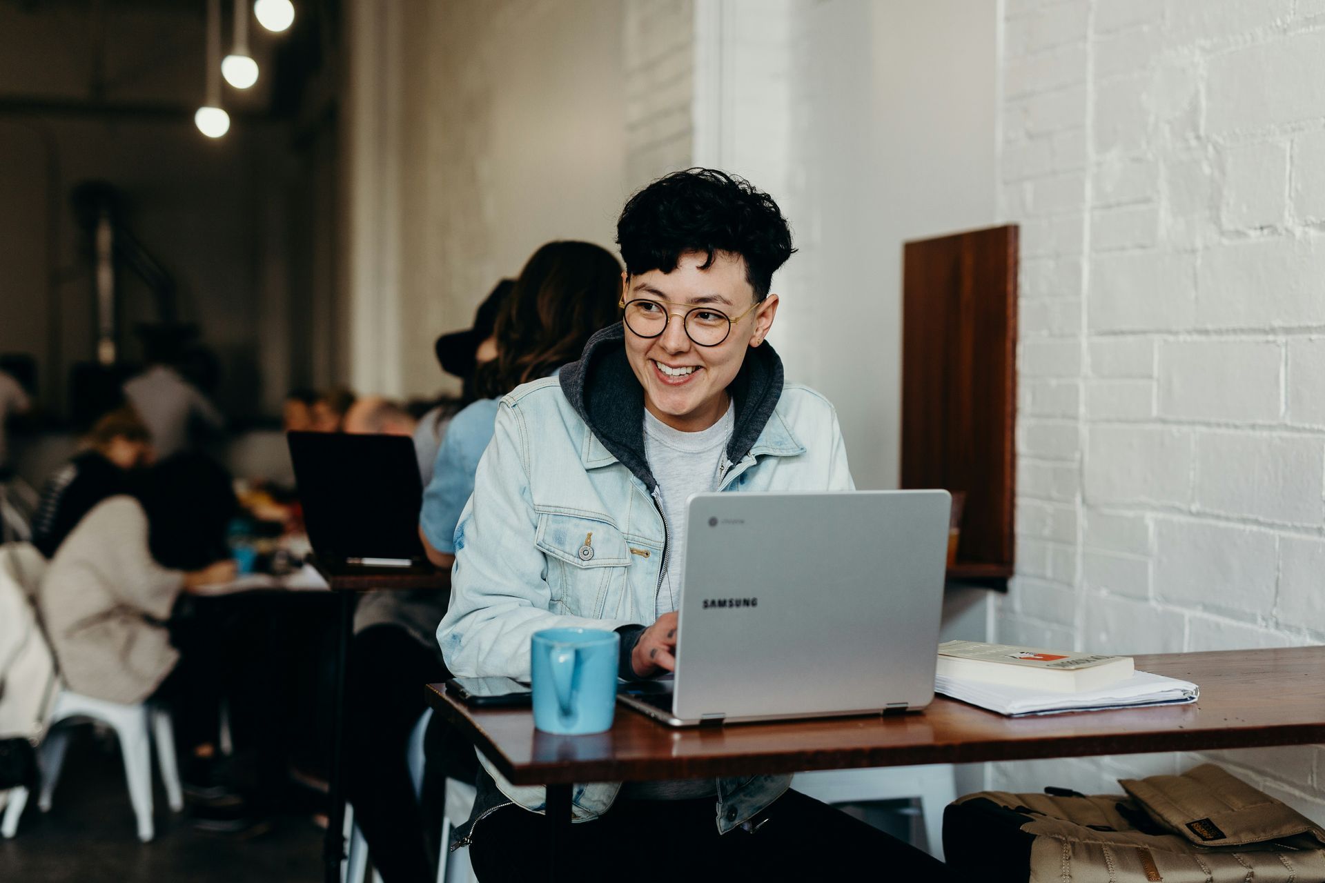 person sitting at laptop smiling with coffee mug