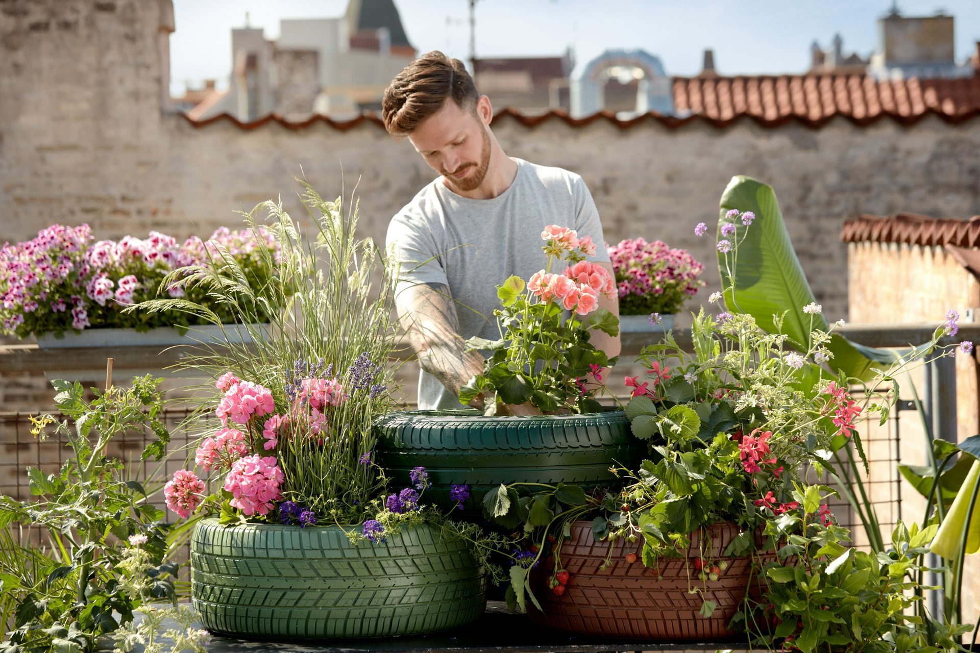 Person planting flowers in tires
