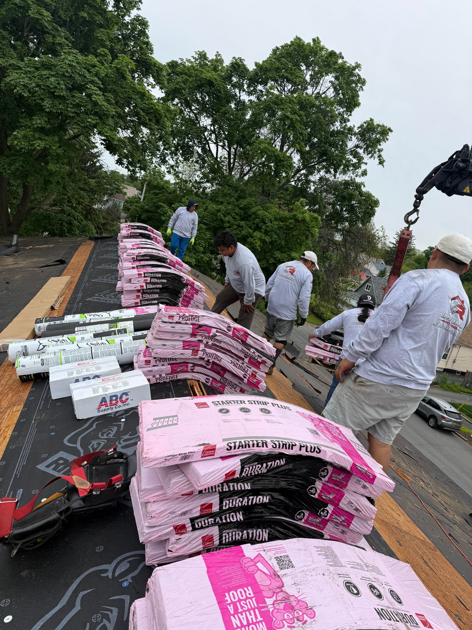 Workers stacking pink-and-white sandbags along a roadside barrier after storm damage