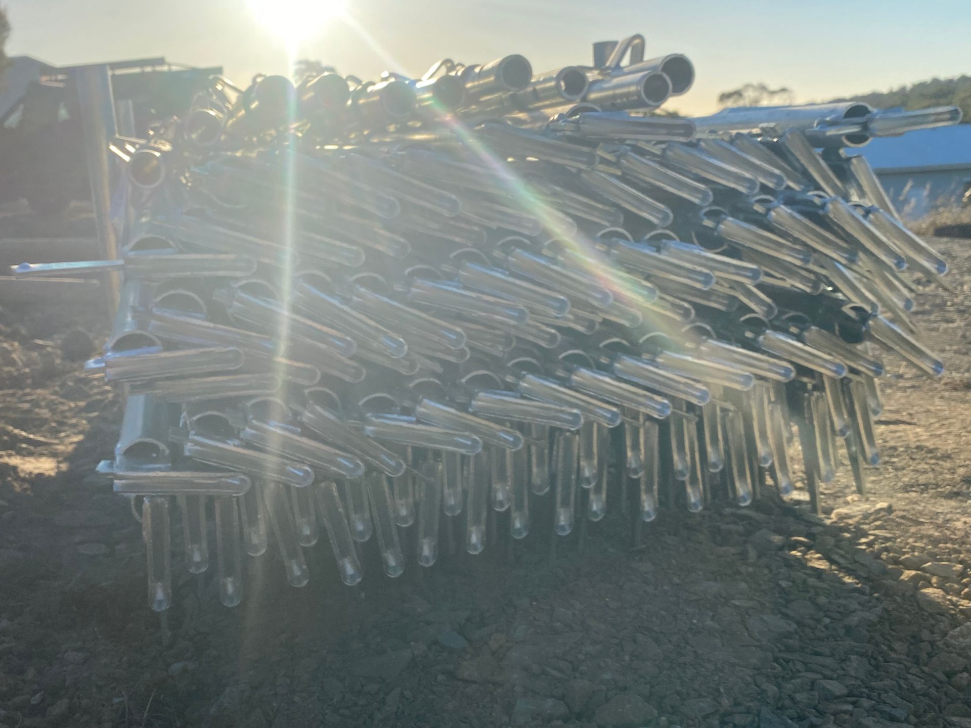 Pile of metal scaffolding pipes stacked outdoors in bright sunlight