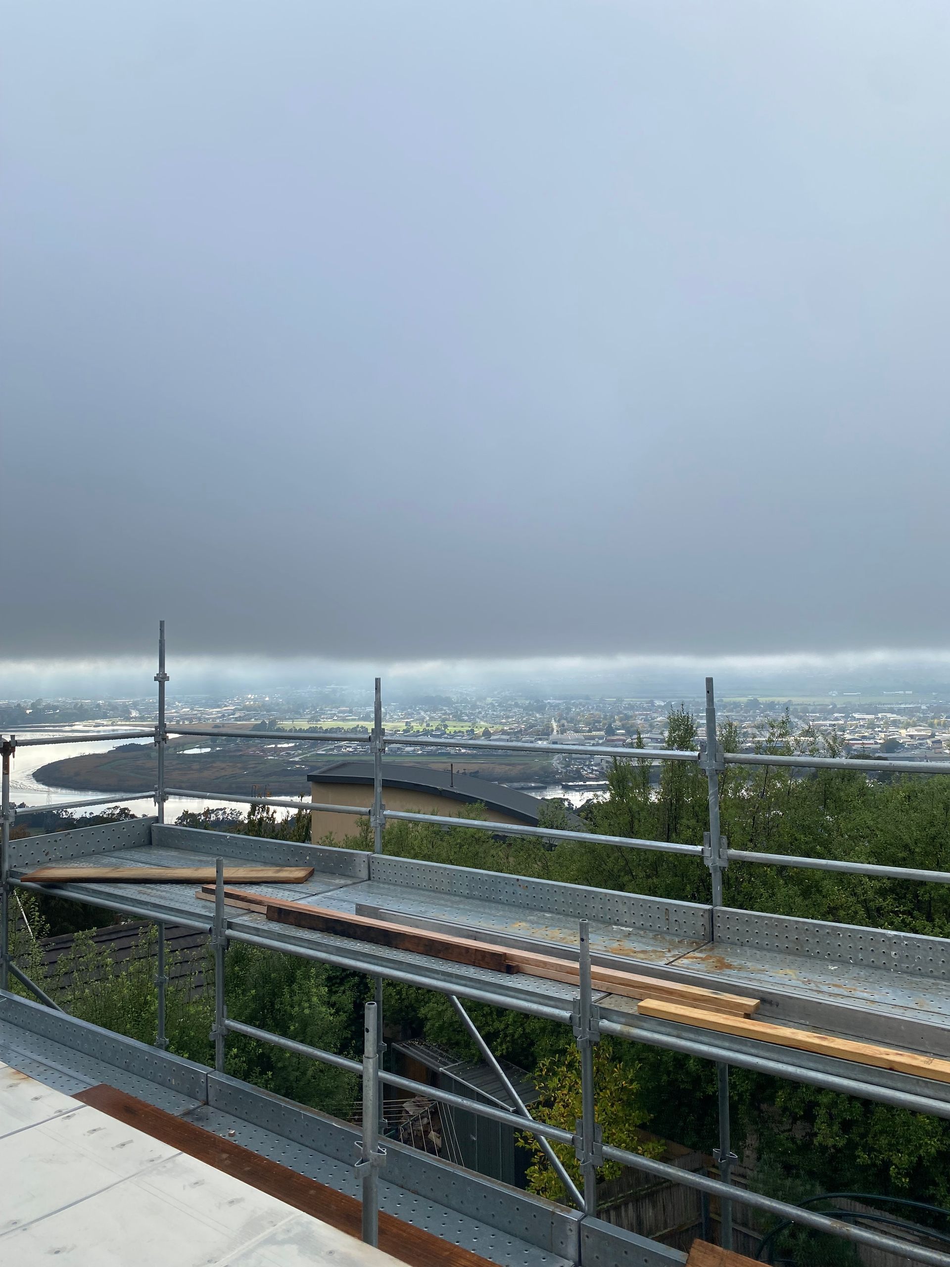 Overlook of a city and river under a gray sky, with a highway bridge in the foreground