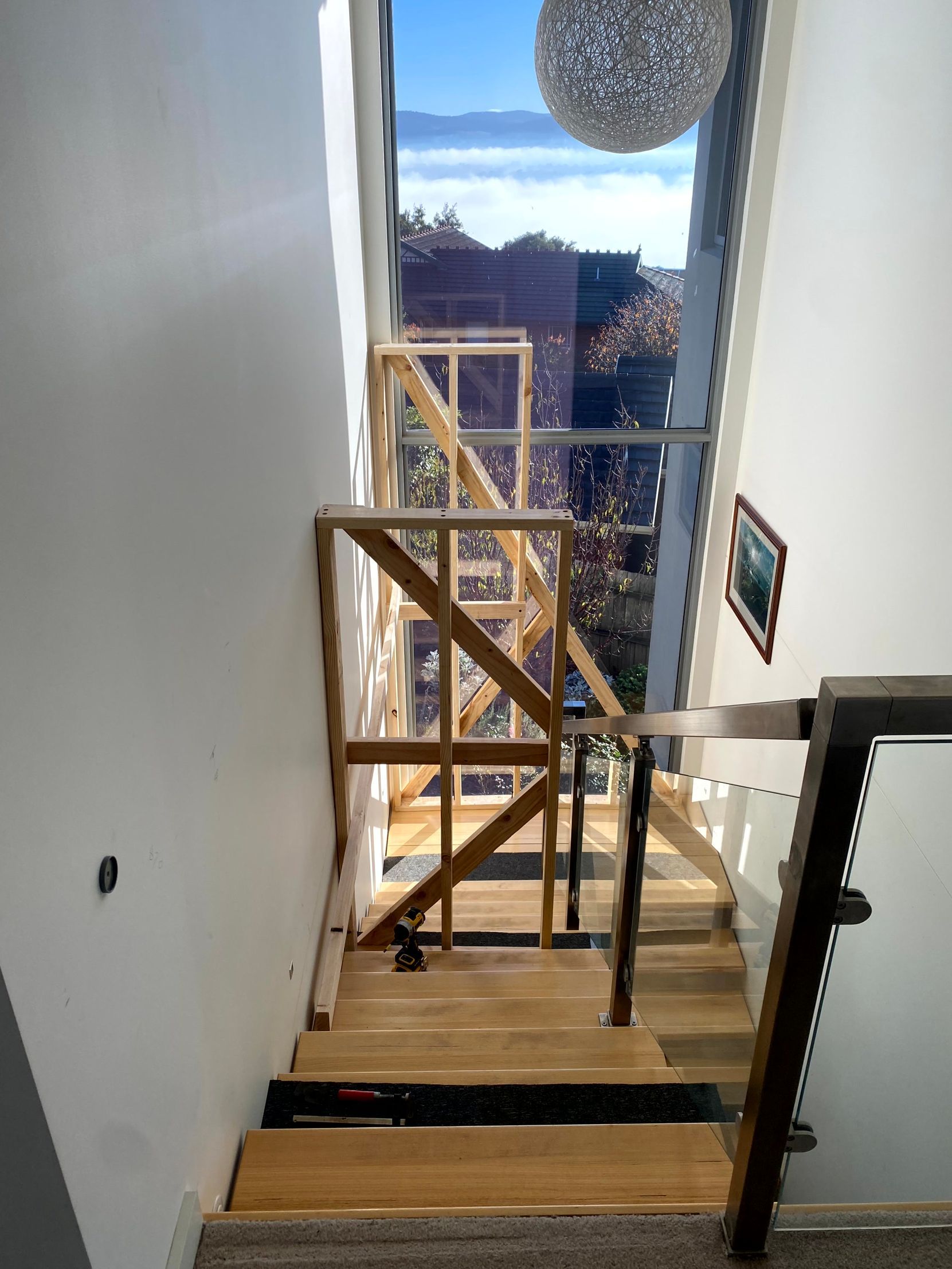 Indoor staircase under construction with wooden safety railings and a bright window at the landing
