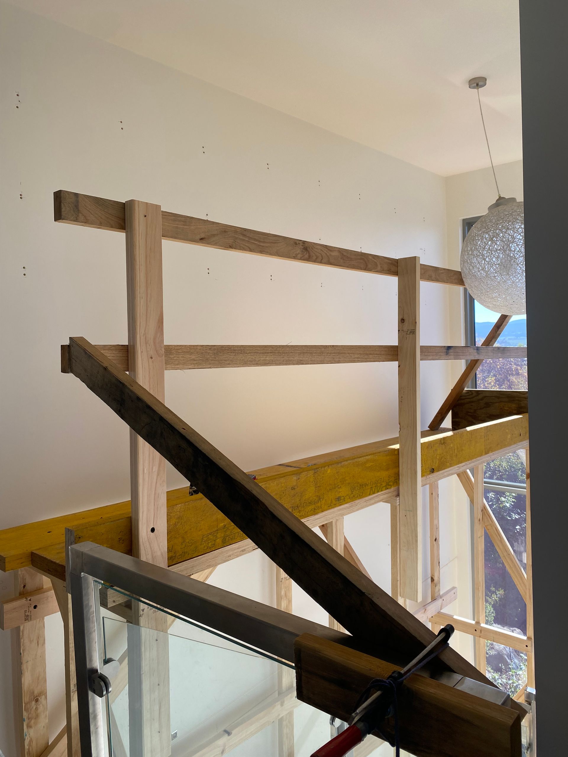 Wooden scaffolding and a black beam inside a stairwell beside a glass door.