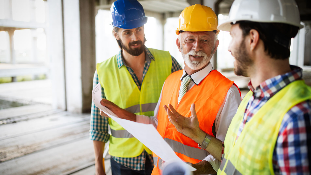 commercial remodeling contractors in an unfinished room speaking to each other over a laptop