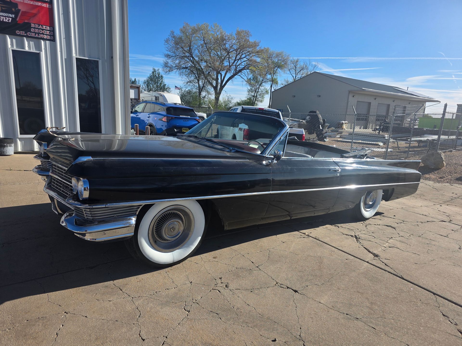 Black classic convertible parked outdoors on a sunny day, side view.