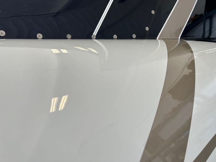 A close up of a white vehicle with a brown stripe on the side