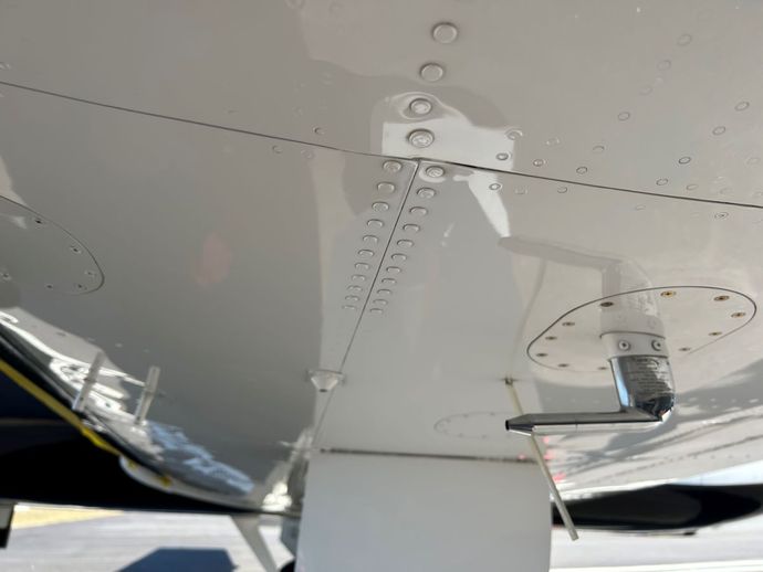 A close up of the underside of a plane with a few screws on it