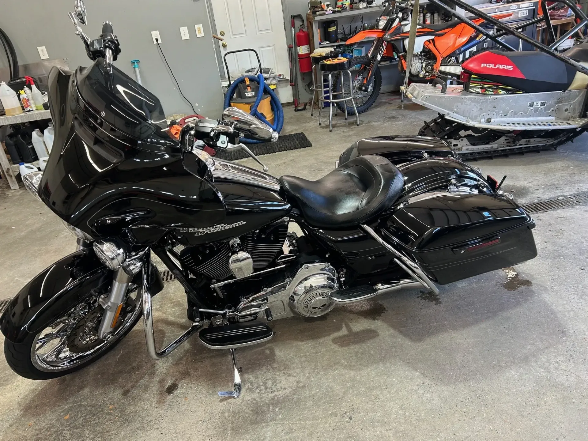 Black touring motorcycle in a garage, shown in side view with chrome accents and saddlebags