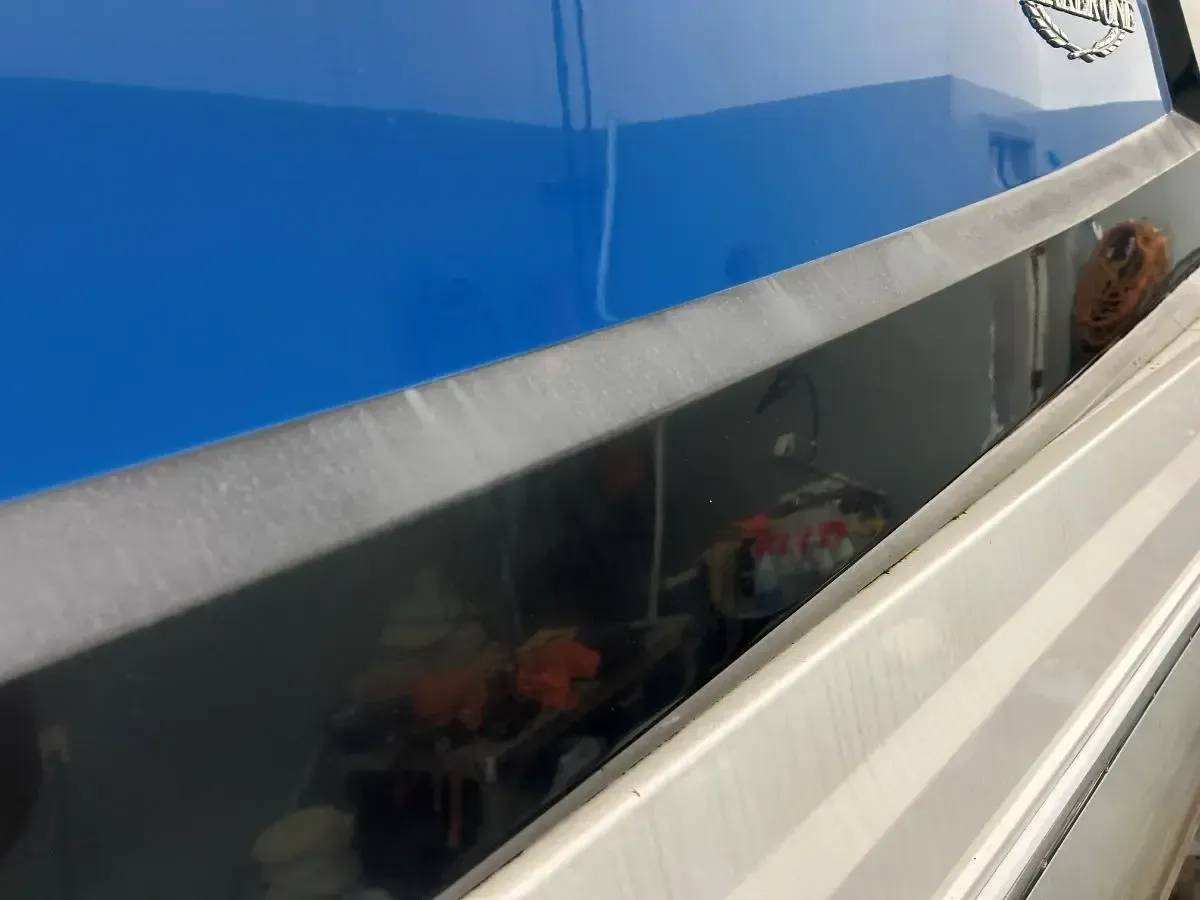 Blue-and-white boat with a slanted window, showing a person inside