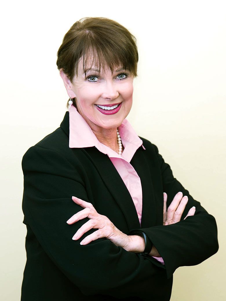 A woman in a black jacket and pink shirt with her arms crossed
