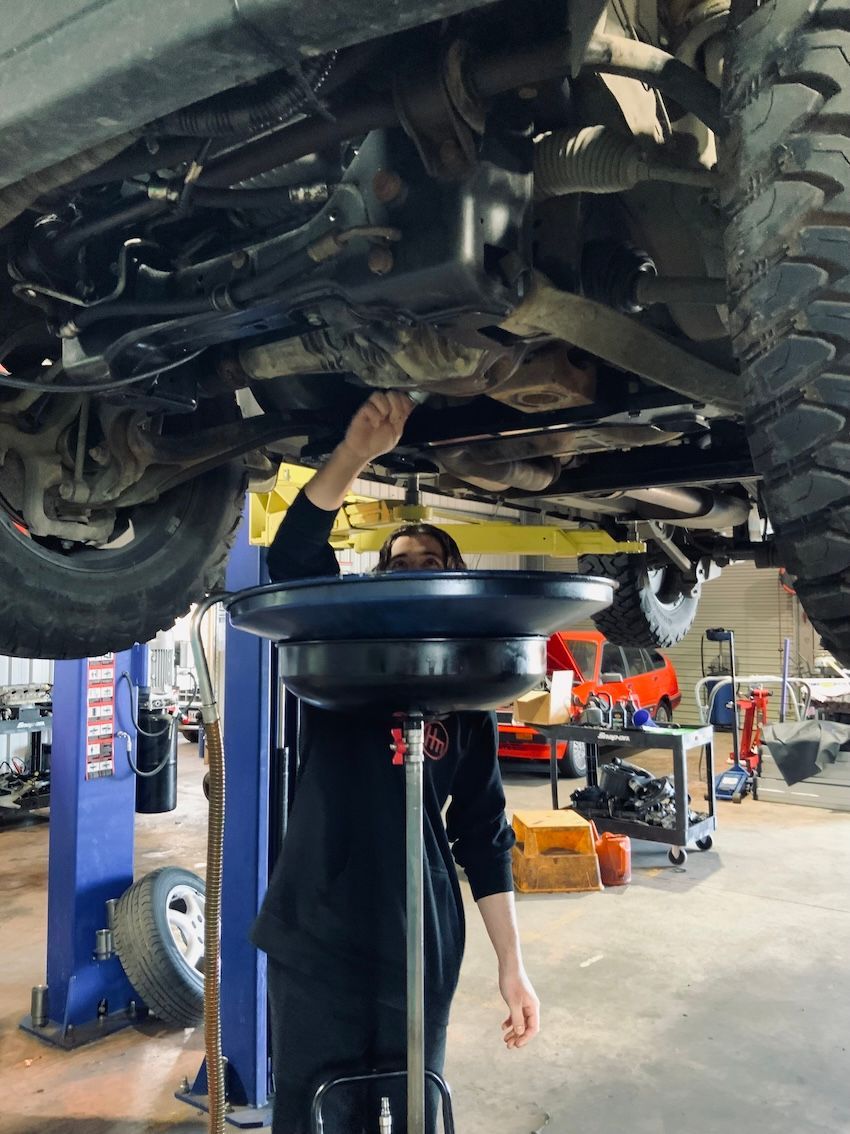 Mechanic Draining Oil Under Car On Hoist — H.M. Mechanical in Drayton, QLD