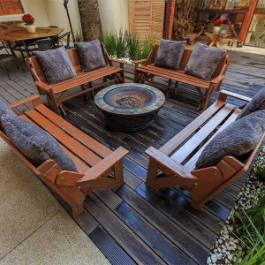 A grey patio sectional and fire pit table set on a balcony overlooking a wooded backyard.