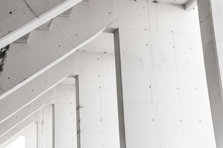 Detalhe arquitetônico em concreto aparente com pilares inclinados, ambiente que pode receber vidros com película para controle solar e estética.