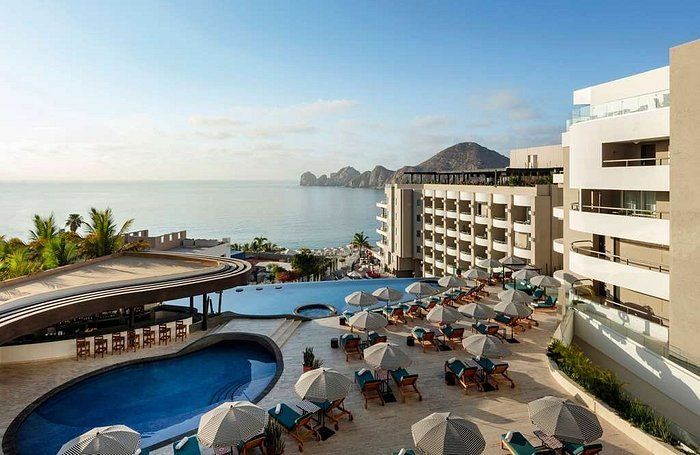 An aerial view of a hotel with a swimming pool and umbrellas.