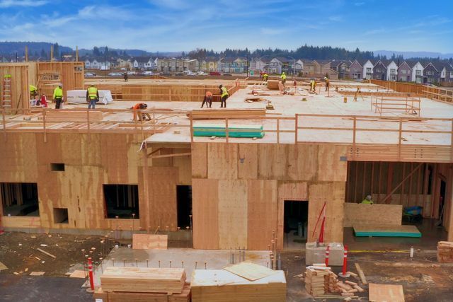 A group of construction workers are working on the roof of a building under construction.