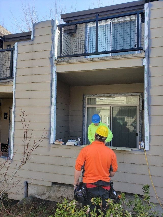 A man in an orange shirt is standing in front of a building