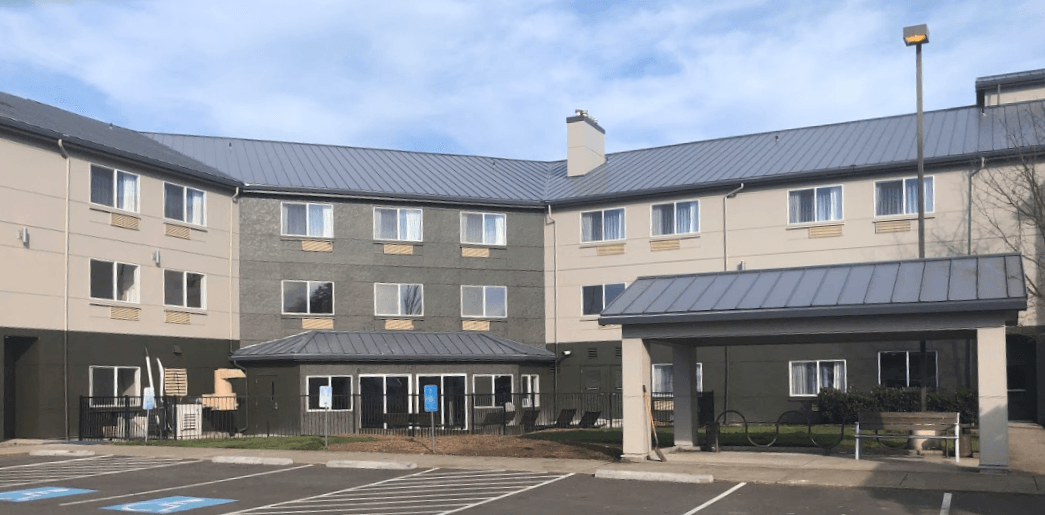A large apartment building with a parking lot in front of it.