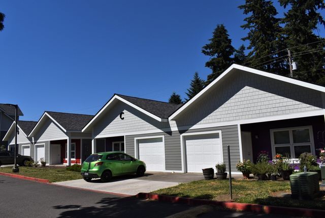 A green car is parked in front of a row of houses.