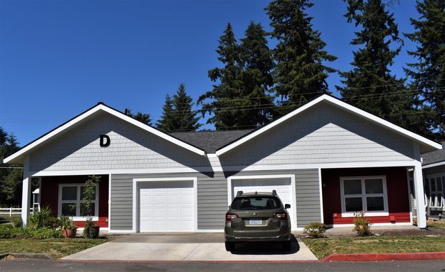 A car is parked in front of a house with two garages.