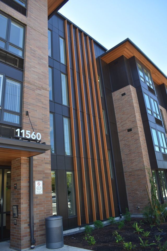 A large brick building with a lot of windows and a trash can in front of it.