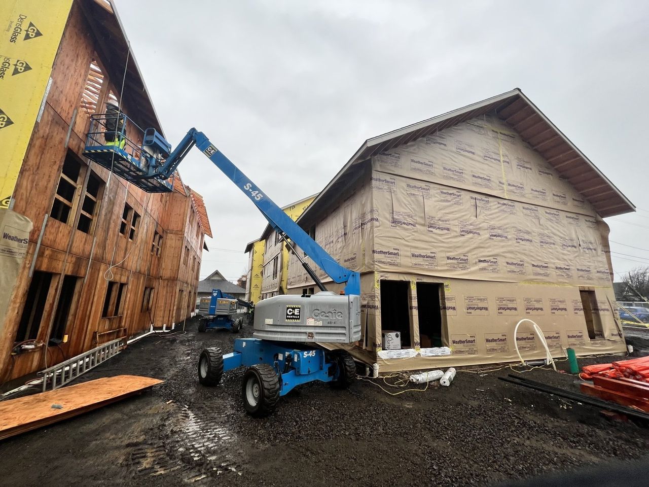 A blue aerial lift is sitting in front of a building under construction.