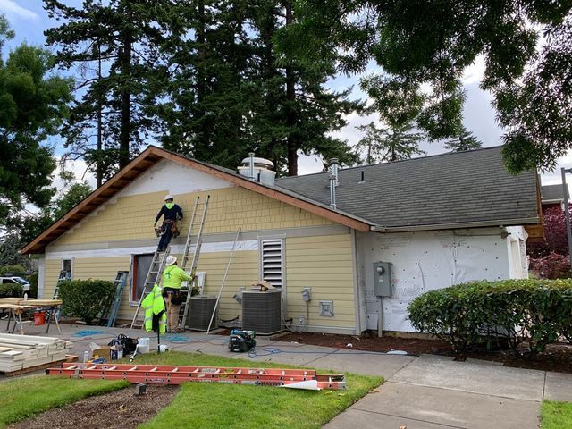 A group of men are painting the side of a house.