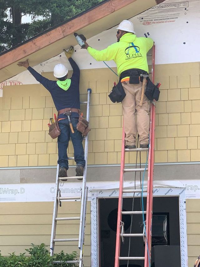 Two men standing on a ladder working on a house