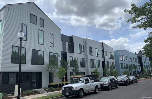 A white truck is parked in front of a row of buildings.