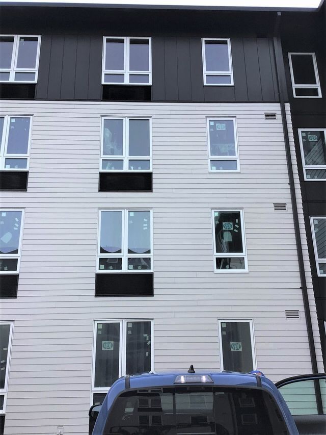 A blue truck is parked in front of a building with a lot of windows.