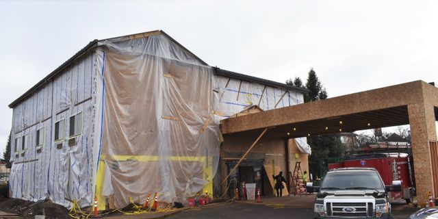 A car is parked in front of a building that is covered in plastic.