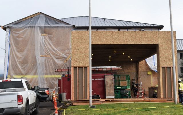A white truck is parked in front of a building under construction.