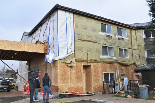 A group of men are standing in front of a building under construction.