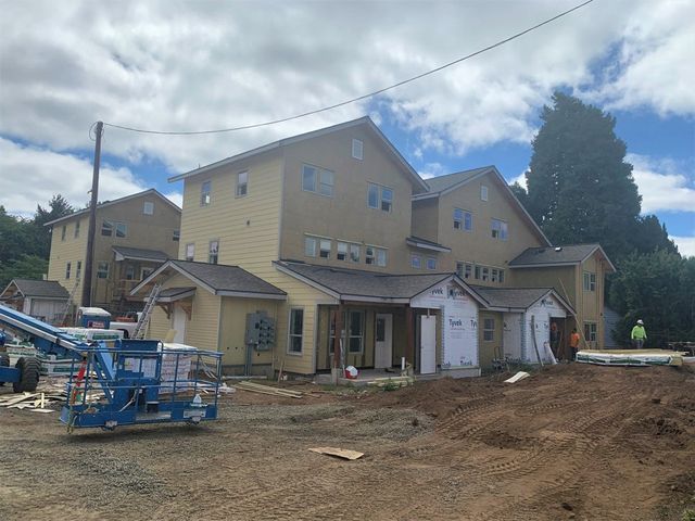 A large house is being built on a dirt lot.