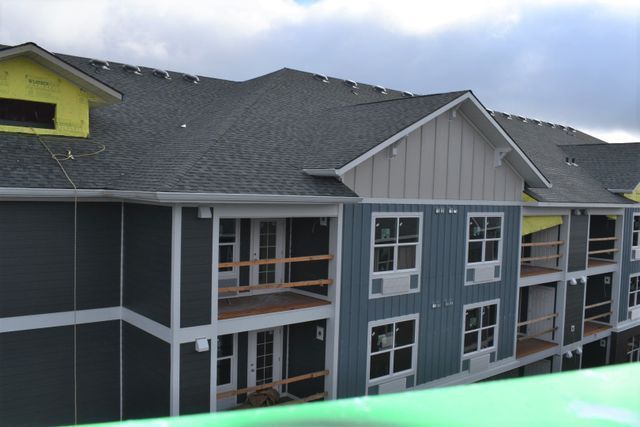 A large apartment building under construction with a gray roof