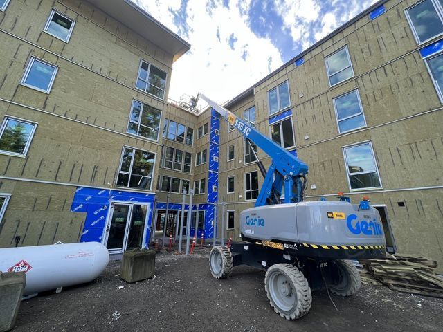 A genie lift is parked in front of a building under construction.