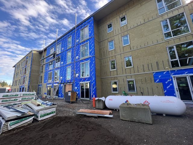 A large building under construction with a propane tank in front of it.
