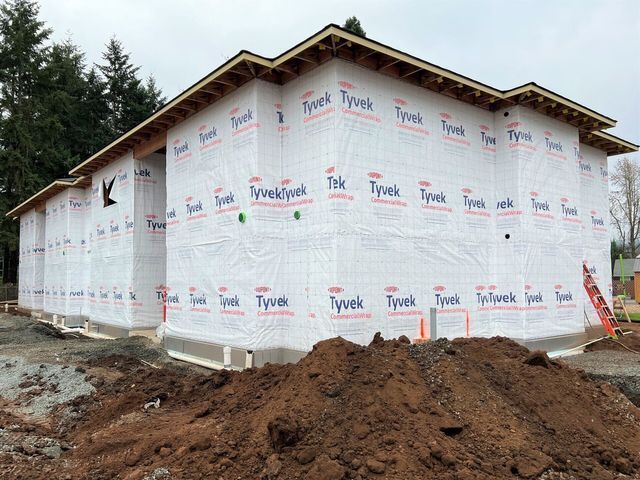 A large pile of dirt is in front of a building under construction.