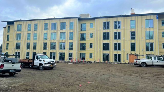 A large building under construction with trucks parked in front of it.
