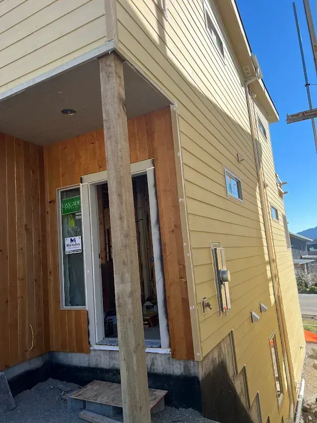 A yellow house with wooden siding is being built.