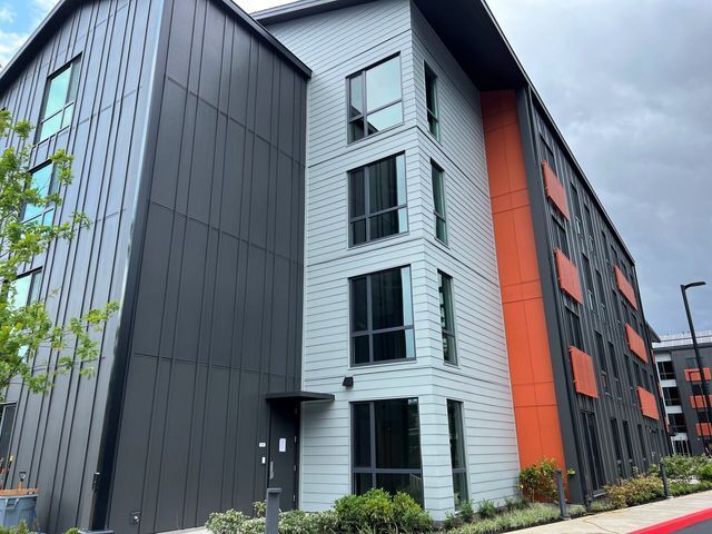 A large apartment building with a lot of windows and a gray and orange facade.