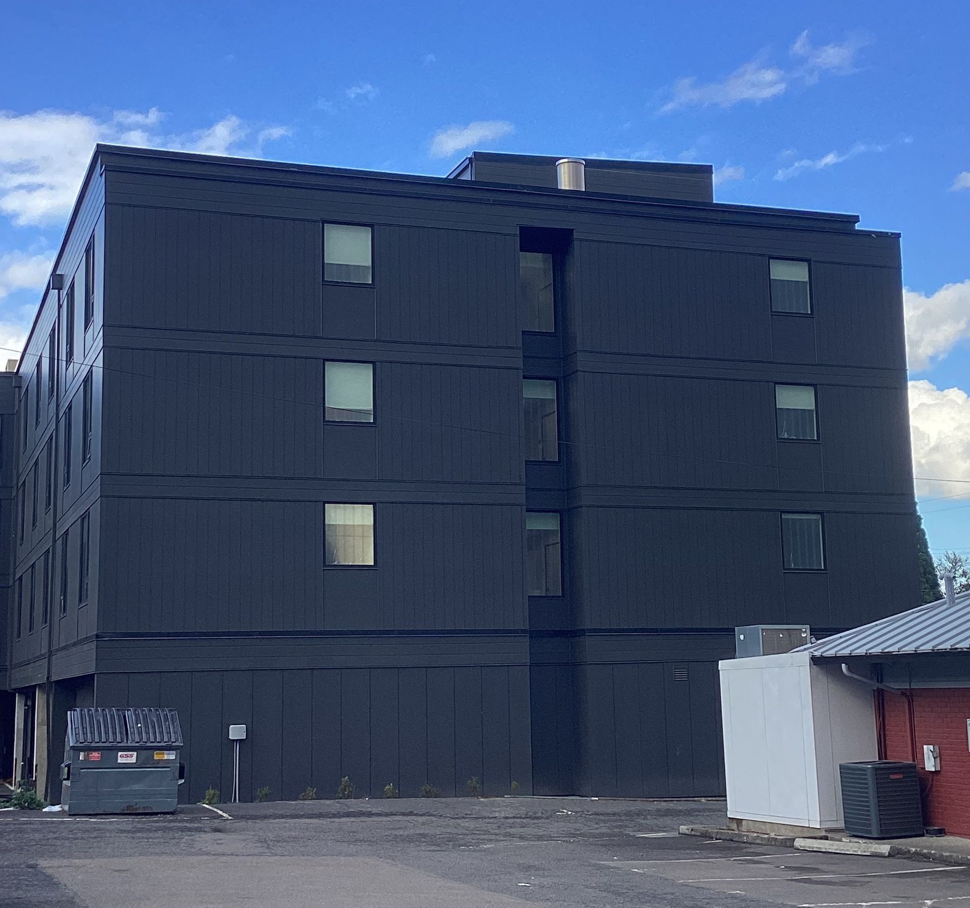 A large black building with a dumpster in front of it