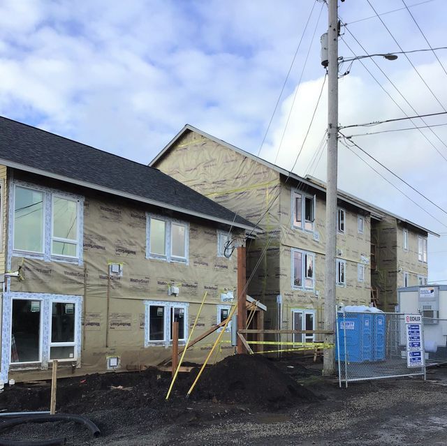 A building under construction with a blue portable toilet in front of it