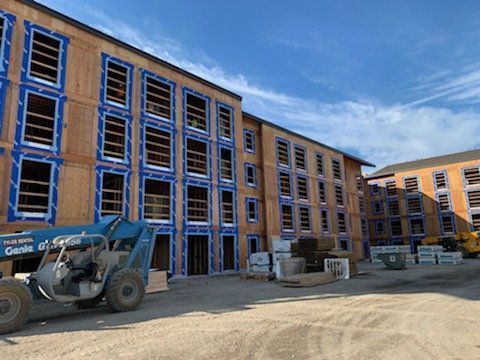 A large building under construction with a tractor parked in front of it.