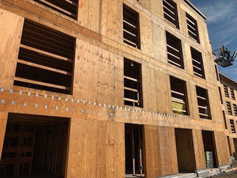 A large wooden building is being built with a crane.