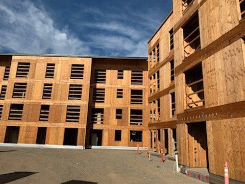 A large wooden building under construction with a blue sky in the background.