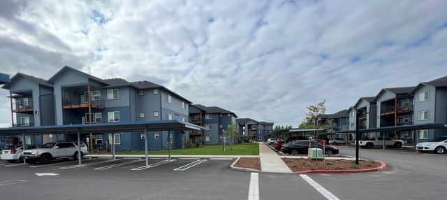 A row of apartment buildings with cars parked in front of them.
