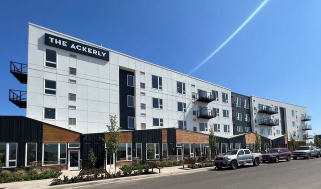 A large apartment building with cars parked in front of it.
