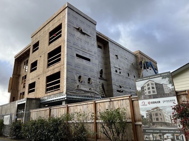 A large building under construction with a wooden fence around it.